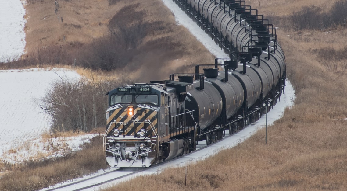 Overhead shot of black freight train transporting oil, moving at high speed on railway tracks