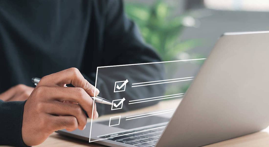 Person sitting in front of a laptop, checking off a box on a digital overlay of a checklist.